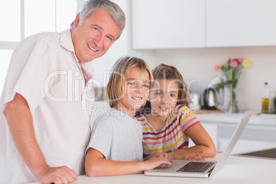 Grandfather and children looking at the camera together with lap