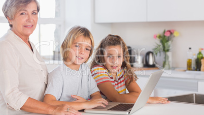 Children and grandmother looking at the camera together with lap