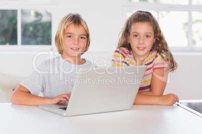 Two children looking at the camera with laptop