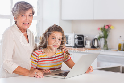 Grandmother and little girl looking at the camera with laptop