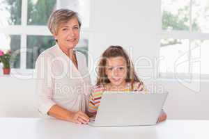 Grandmother and child looking at camera together with laptop