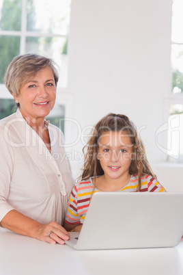 Smiling grandmother and child looking at camera together with la