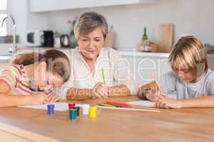 Granny and her grandchildren drawing seriously