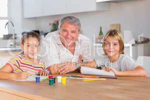 Grandfather and her grandchildren smiling at the camera with dra