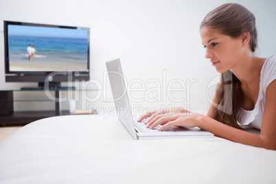 Woman on her laptop with television in the background