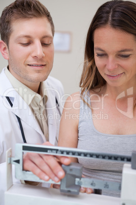 Doctor helping patient to adjust scale