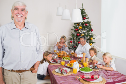 Smiling grandfather standing at the dinner table