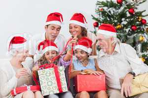 Family watching little girl opening christmas present