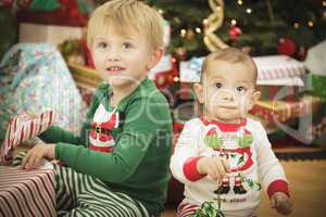 Baby and Young Boy Enjoying Christmas Morning Near The Tree