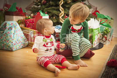 Baby and Young Boy Enjoying Christmas Morning Near The Tree