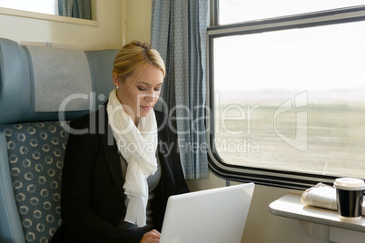 Woman using laptop traveling by train commuter