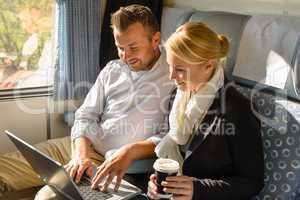 Woman and man relaxing in train laptop