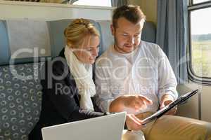 Woman and man in train laptop clipboard