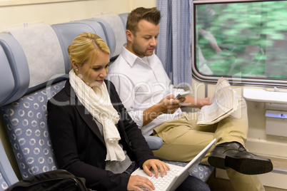 Woman with laptop man newspaper in train
