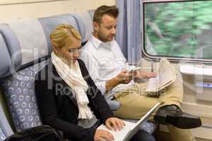 Woman with laptop man newspaper in train