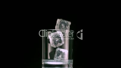 Three ice cubes falling into a glass