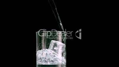 Water filling a glass with ice cubes