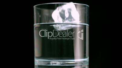 Three ice cubes overfilling a water glass