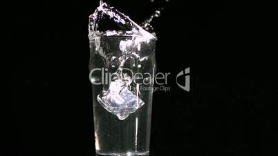 One ice cube overfilling a water glass