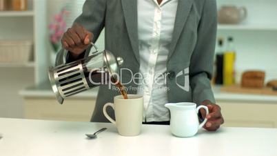 Woman adding milk to coffee in the kitchen