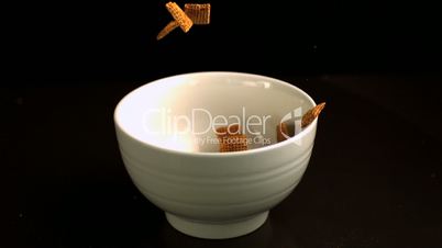 Square cereal pouring into a white bowl