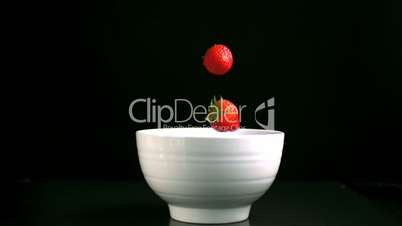 Strawberries falling in a white bowl