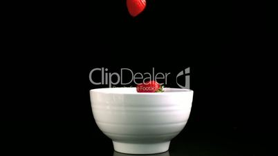Strawberries falling in a bowl