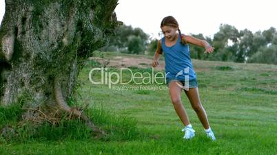 Young child running around a big tree