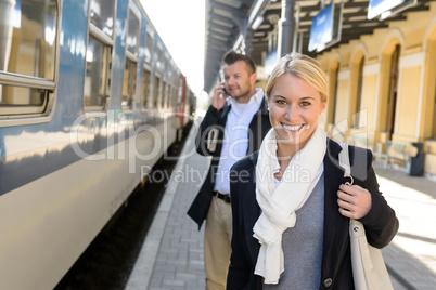 Woman smiling in train station man phone