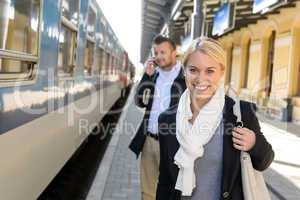 Woman smiling in train station man phone