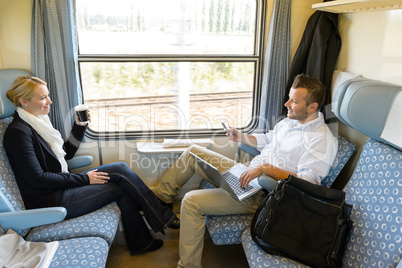 Man and woman sitting in train talking