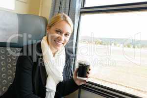 Woman smiling sitting in train holding coffee