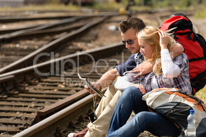 Couple looking at map sitting on railroad