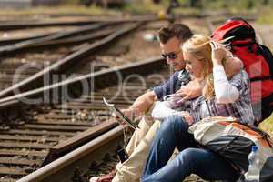 Couple looking at map sitting on railroad