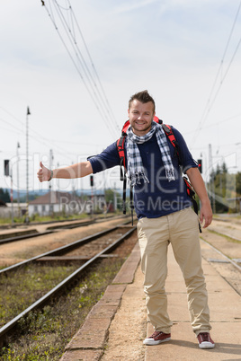Man hitchhiking on railroad train station smiling