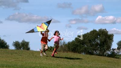 Two children running with kite in park