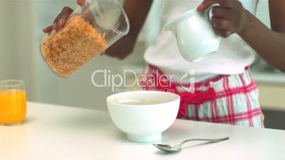 Woman pouring milk and cereal into bowl