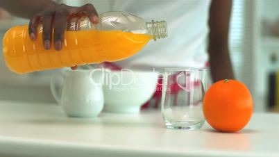 Woman pouring orange juice into glass at breakfast