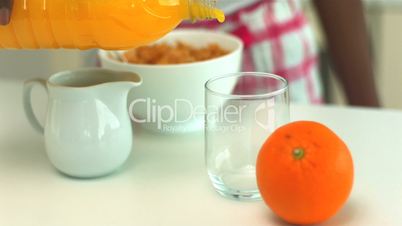 Orange juice being poured into a glass at breakfast