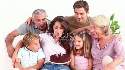 Family blowing candles on chocolate cake