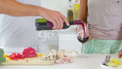 Husband pouring red wine in kitchen