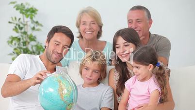 Multi-generation family all looking at globe
