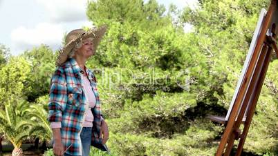 Elderly woman painting in the park