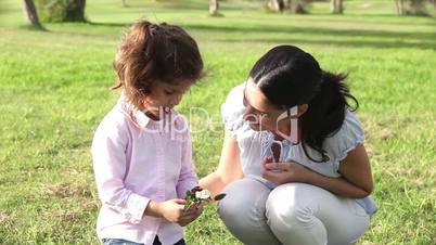 Little girl smelling a flower with mother