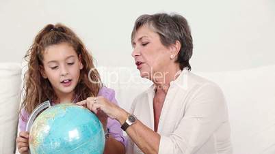 Grandmother using a globe with her granddaughter