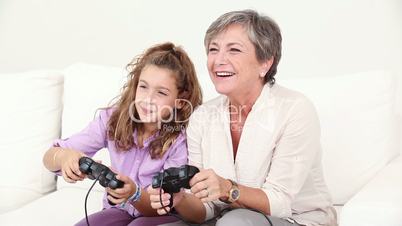 Grandmother playing at the video games with his granddaughter