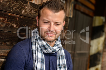 Pensive attractive man leaning against wooden wall