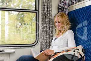 Woman reading book in train smiling commuter