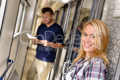 Woman smiling and man reading in train