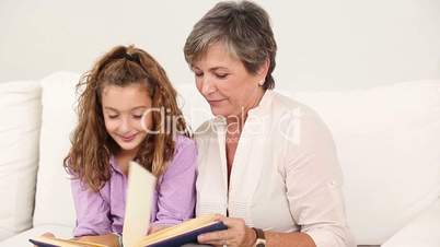Little girl reading a book with her grandmother